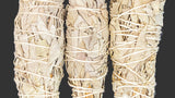 Three bundles of sage wrapped in twine on a dark background