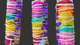 Three colorful smudge sticks with floral elements on a grey surface