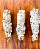 Three sage smudge sticks on a wooden surface