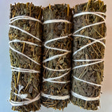 Three bundles of black sage tied with white string on a light background