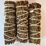 Three bundles of juniper tied with twine on a light background