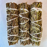 Three bundles of rosemary tied together on a light background