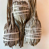 Three bundles of sage tied with twine on a light background