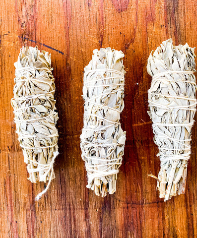 Three sage smudge sticks on a wooden surface